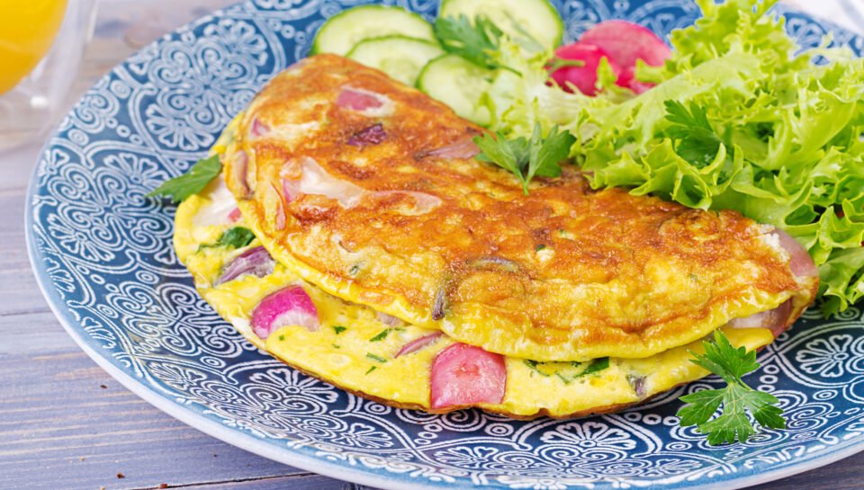 Breakfast. Omelette with radish, red onion and fresh salad on blue plate.  Frittata - italian omelet.